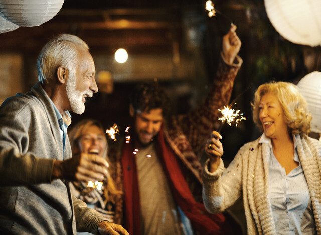 senior couple dances with sparklers under paper lanterns during a celebration