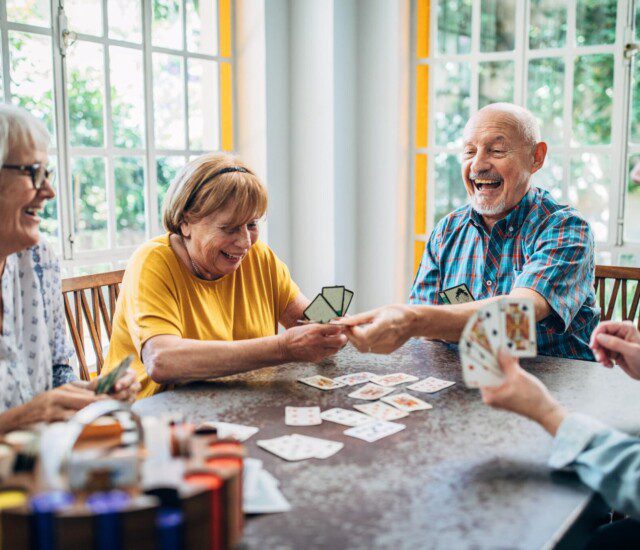 group of senior friends play cards together