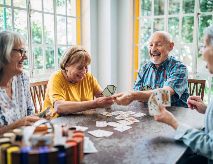 group of senior friends play cards together