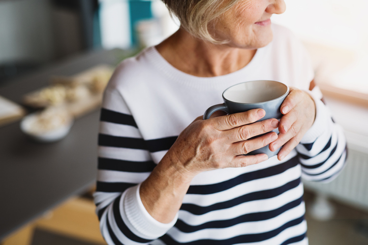 close-up of senior woman in striped shirt holding coffee mug