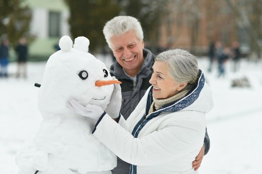 couple building a snowman together on a snowy day