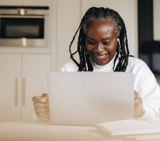 Senior woman sitting with a laptop computer in front of her.