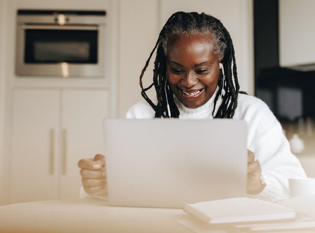 Senior woman sitting with a laptop computer in front of her.