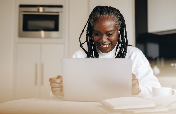 Senior woman sitting with a laptop computer in front of her.