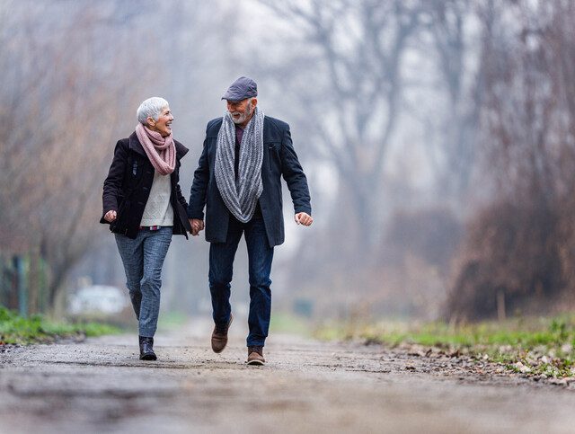 Senior couple holding hands and walking through nature together