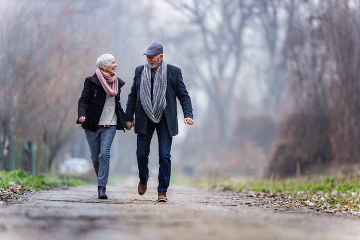 Senior couple holding hands and walking through nature together