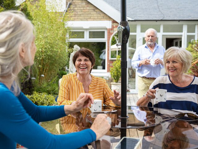 Senior friends having coffee together and chatting outdoors