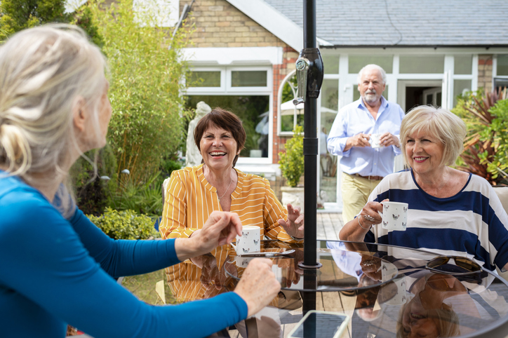 Senior friends having coffee together and chatting outdoors