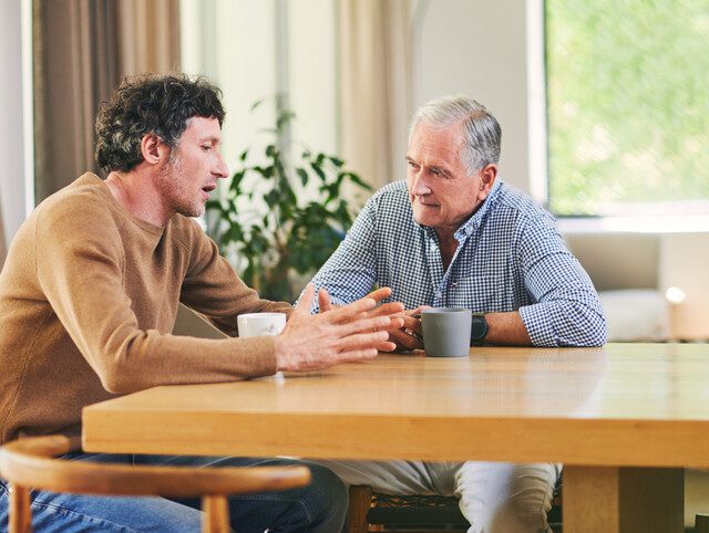 Senior man having a conversation with his adult son.